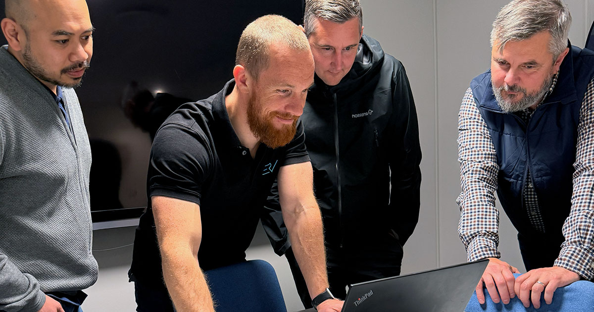 Fire personer følger med på en bærbar PC under test av første leveranse i Fase II hos ERV.